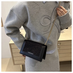 Détail du sac à bandoulière noir pailleté avec chaîne dorée et texte mode chic
