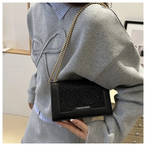 Détail du sac bandoulière à paillettes noires avec chaîne dorée et logo Fashion & Bags