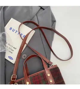 Detailed top view of a red and green plaid wool tote bag with brown leather straps