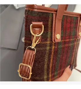Close-up of golden hardware and retro plaid wool texture on a stylish bucket bag