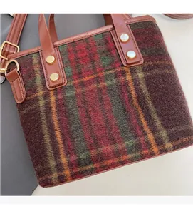 Close-up of retro plaid wool handbag fabric with brown leather base and golden hardware