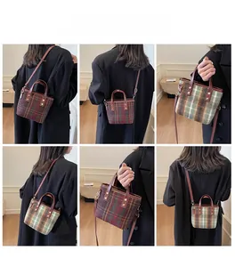 Detail view of vintage plaid tote bag with leather handles and metallic buckles