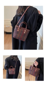 Detail of vintage plaid wool bucket bag with leather handles and gold metal rivets