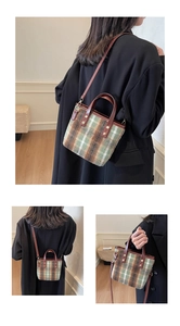 Detail of vintage green plaid tweed bucket bag showing leather handles and gold metal buckles