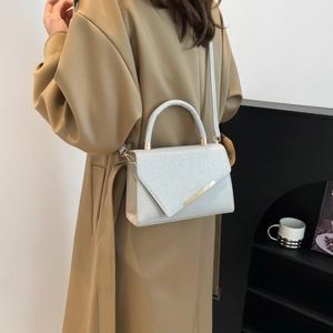 Silver glitter crossbody bag with metallic trim shown on trench coat model