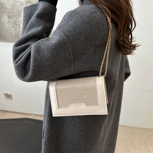 Sac bandoulière élégant doré champagne avec logo sur garniture blanc cassé et chaîne