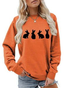 Detail of bright orange oversized sweatshirt featuring black rabbit silhouettes and ribbed cuffs