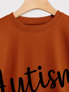 Close-up of brown crewneck sweatshirt with black Autism script print on ribbed collar