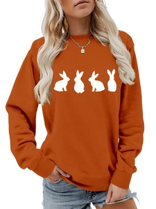 Detail of orange crewneck sweatshirt featuring white rabbit silhouettes and ribbed cuffs