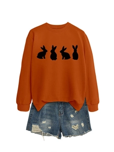 Detail of orange crewneck sweatshirt with four black rabbit silhouettes and denim shorts