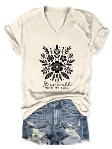 Détail du t-shirt crème à col en V avec motif floral et inscription inspirante