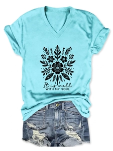 Détail d'un t-shirt bleu clair à col en V avec imprimé floral et texte It is well with my soul