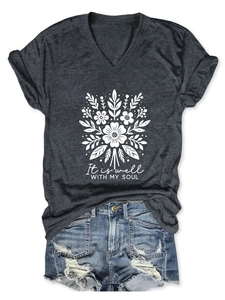 Détail du t-shirt gris col en V avec texte et short en jean aux bords effilochés