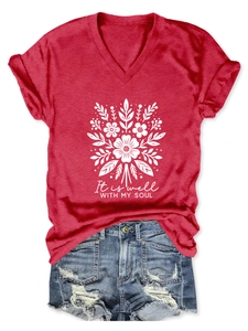 Détail du t-shirt rouge à col en V avec imprimé floral et short en jean déchiré