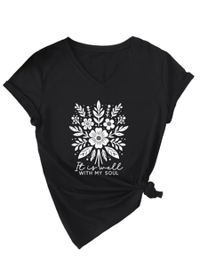 Détail d'un t-shirt noir col en V avec imprimé floral et finition nouée à l'ourlet