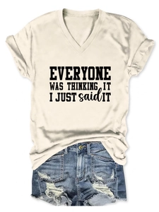 Détail du t-shirt beige à col en V avec slogan noir et short en jean vieilli et usé