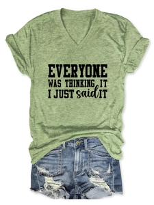 Détail du t-shirt vert col en V avec slogan noir et short en jean délavé