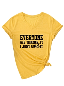 Détail du t-shirt jaune à col en V avec texte imprimé et ourlet noué sur le côté