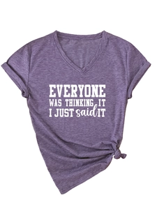 Détail du t-shirt violet à col en V avec slogan blanc et nœud élégant à l'ourlet du bas