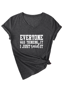 Détail d'un t-shirt gris foncé à col en V avec slogan blanc et nœud à l'ourlet