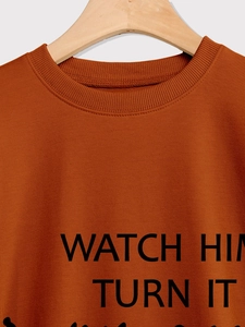 Close-up of caramel crewneck sweatshirt with WATCH HIM TURN IT text on ribbed neckline