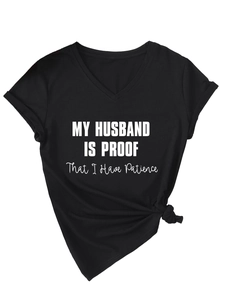 Close-up of black V-neck T-shirt with 'MY HUSBAND IS PROOF' text and knotted hem detail