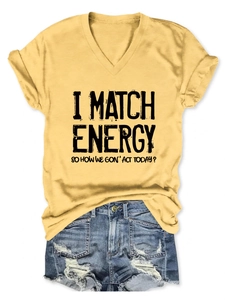 Detail of yellow V-neck t-shirt featuring black slogan and denim shorts outfit