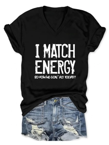 Flat lay of V-neck T-shirt with 'I Match Energy' text and distressed denim shorts