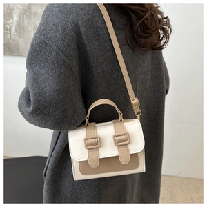 Detail of a two-tone crossbody bag featuring vintage buckles and contrast stitching