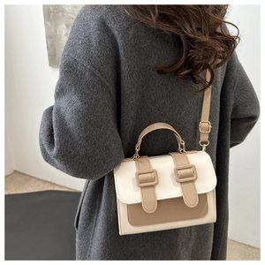 Detail of color-block crossbody bag on shoulder, ivory and khaki faux leather style