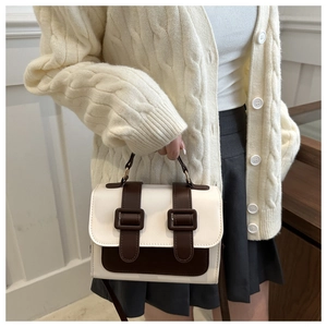 Detail of a retro contrast shoulder bag with dual buckles on a minimalist chic outfit