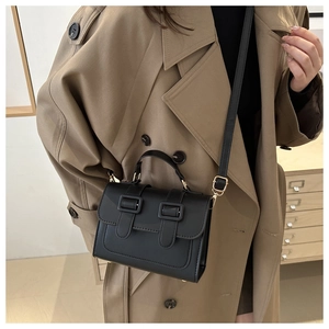 Classic black leather crossbody bag styled with a khaki trench coat for a chic look