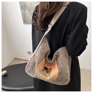 Detail of corduroy tote bag featuring cat embroidery and adjustable nylon strap