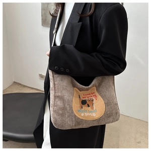 Close-up of grey corduroy shoulder bag featuring cute cat embroidery patch detail