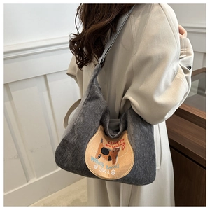 Detail of grey corduroy shoulder bag featuring a cute cat embroidery and text