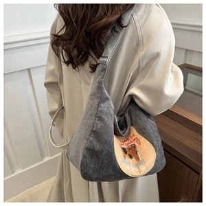 Detail of grey fabric hobo bag featuring embroidered cartoon cat and heart pattern