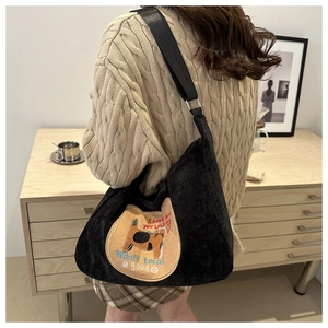 Detail of black corduroy hobo bag with cat embroidery and adjustable shoulder strap