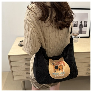 Close-up of black corduroy tote bag featuring a cute cat embroidery patch and silver buckle