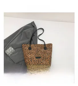 Detail view of leopard print tote bag featuring black slim straps and textured fabric surface