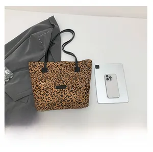 Size comparison of leopard print tote bag with tablet and phone on white background