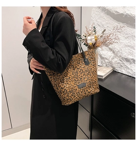 Close-up of leopard print tote bag with black leather patch shown on a stylish model