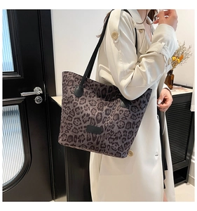Detailed view of leopard print tote bag with black straps worn by a model in a room