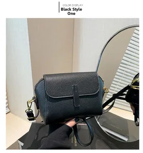 Detail view of black lychee grain leather handbag with gold metal clasp and vertical strap