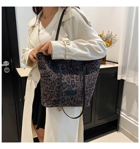 Detail of gray leopard print tote bag with black handles on a model in trench coat