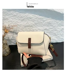 Detail of white litchi pattern leather bag with brown strap and gold metal buckle