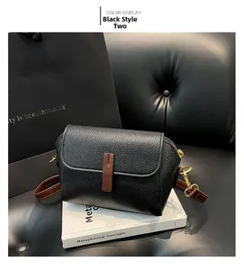 Close-up of black lychee leather crossbody bag with brown trim and gold metal hardware