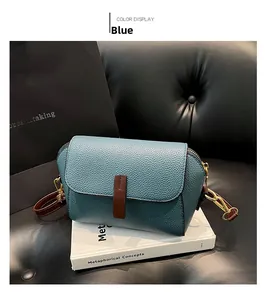 Detail of blue pebble grain leather crossbody bag with brown trim and gold hardware
