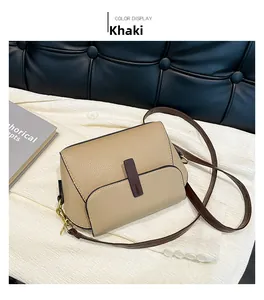 Detail of khaki pebbled leather crossbody bag with brown trim and gold hardware