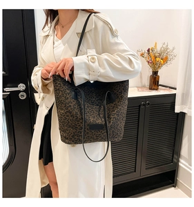Leopard print tote bag with black leather straps styled with a white trench coat