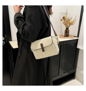Chic off-white lychee grain leather crossbody bag with brown trim shown on a model